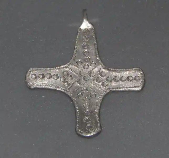 A silver cross pendant with dotted texture